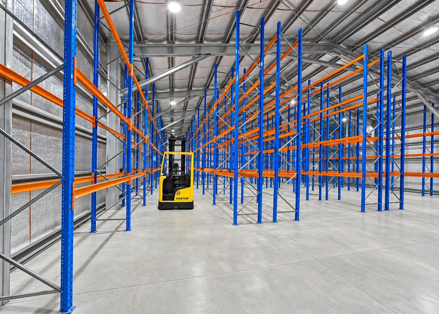 Warehouse with blue and orange pallet racking and a yellow Hyster forklift